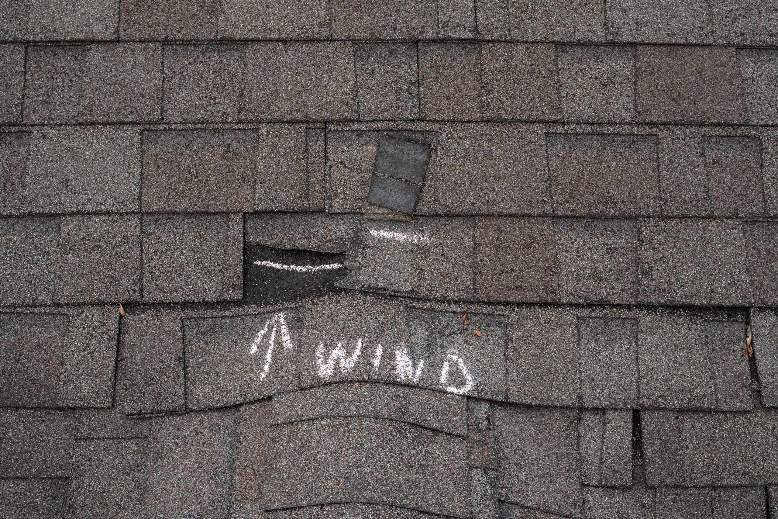 Superstorm Roofing crew inspecting wind damage on a residential roof