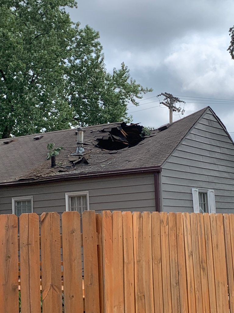 Wind-blown shingles and exposed roof decking on an Iowa home