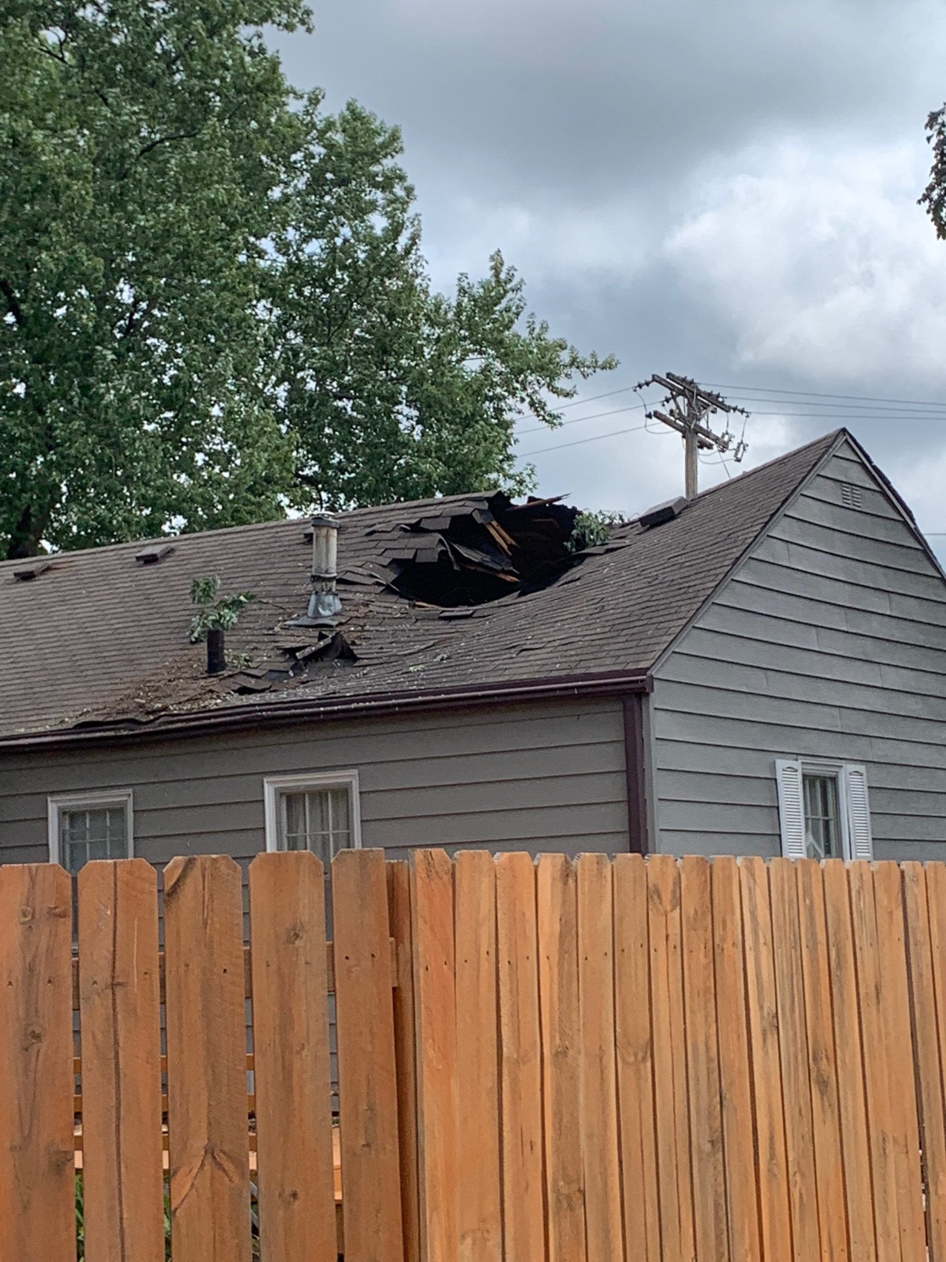 Wind-blown shingles and exposed roof decking on Iowa home